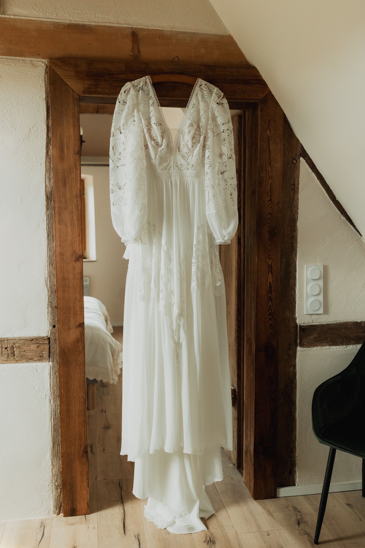 Robe de mariée suspendue dans une chambre à colombages du Domaine Imodis à Saessolsheim