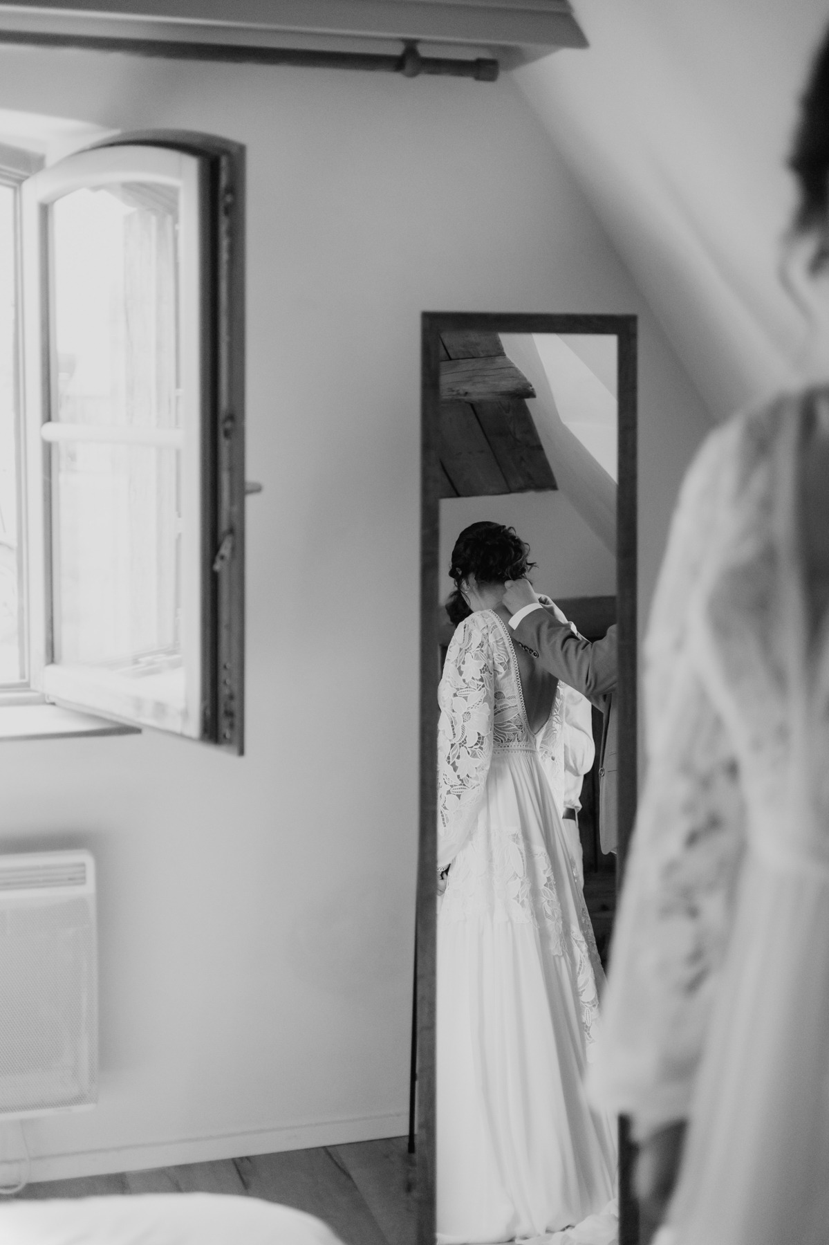 Mariée se préparant près de la fenêtre à volets d'une chambre du Domaine Imodis à Saessolsheim