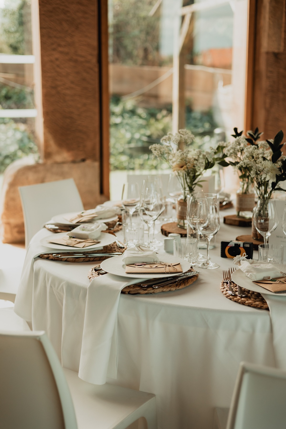 Table dressée près d'une baie vitrée avec vue sur la verdure au Domaine Imodis