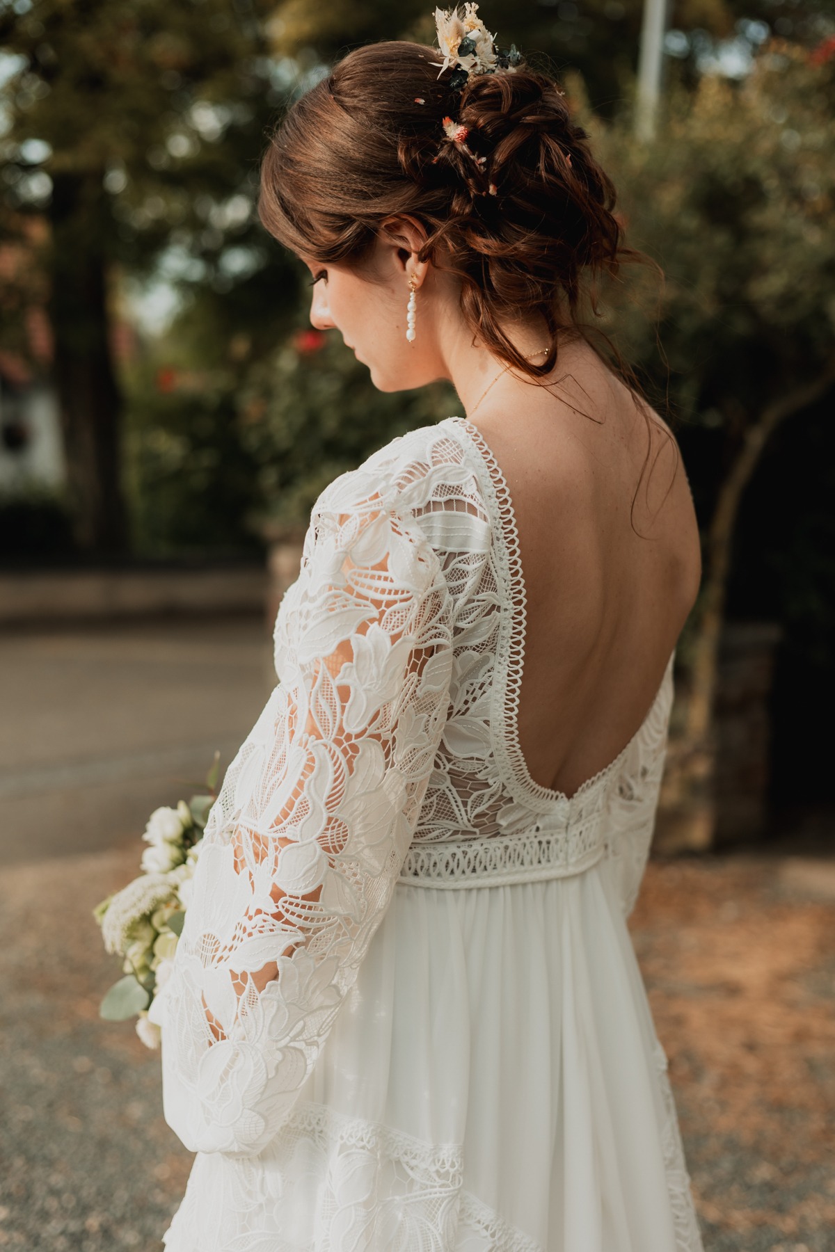Détail de la robe en dentelle et de la coiffure de la mariée au Domaine Imodis à Saessolsheim