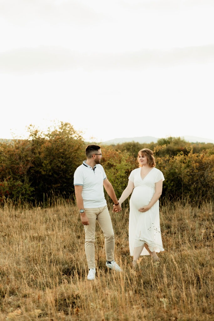 Séance photo grossesse en extérieur en Alsace : futurs parents complices au coucher du soleil sur le Bollenberg