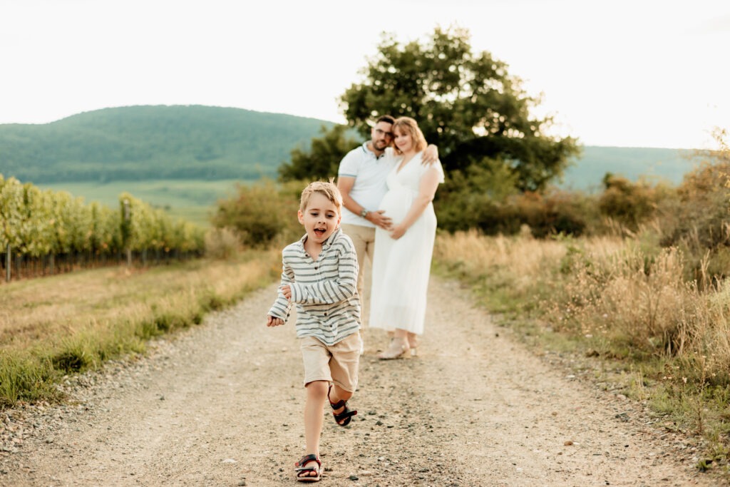 Séance maternité en famille en extérieur au Bollenberg : balade sur le chemin, vignes en arrière-plan